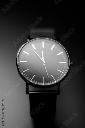 black modern analog wristwatch on a black background