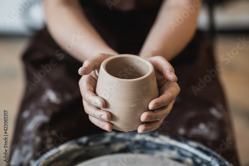 Hands of a potter, creating an earthen jar on the circle