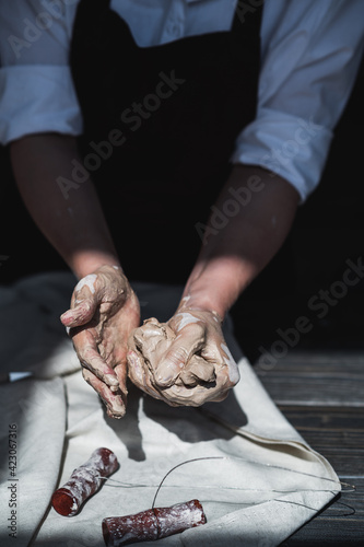 Woman's hands wet and dirty after working with clay in a pottery studio