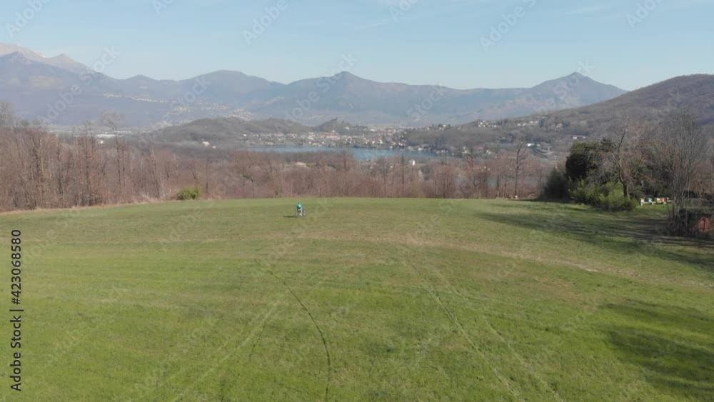 Aerial: man having fun by riding mountain bike in the grass on sunny day, scenic alpine landscape, fitness wellbeing sport in nature, native flat color profile Aerial: man having fun by riding mountain bike in the grass on sunny day, scenic alpine landscape, fitness wellbeing sport in nature, native flat color profile