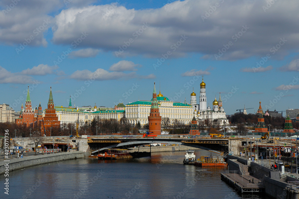 View of the reconstructed Bolshoi Kamenny Bridge across Moscow river and the Moscow Kremlin on a sunny sky with white clouds. Travel concept.