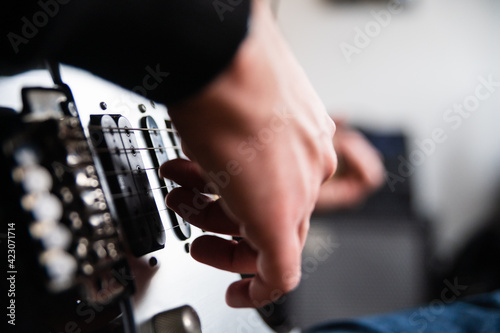 Low angle side view of concentrated blind guitarist playing music instrument while rehearsing melody at home