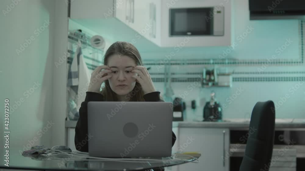 Close-up of worried woman talking on video call using laptop while working from home. Young brunette use laptop computer at transparent dining table during remotely works at home Close-up of worried woman talking on video call using laptop while working from home. Young brunette use laptop computer at transparent dining table during remotely works at home