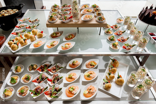 Business lunch at business meeting close up. View of buffet table with different salads and sandwiches in small white plates for quick snack