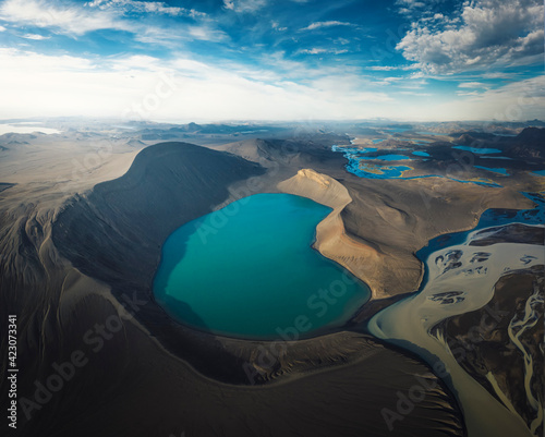 Wonderful scenery of crystal clear lake on vulcan crater surrounded by rough mountain range covered with dry vegetation on clear day