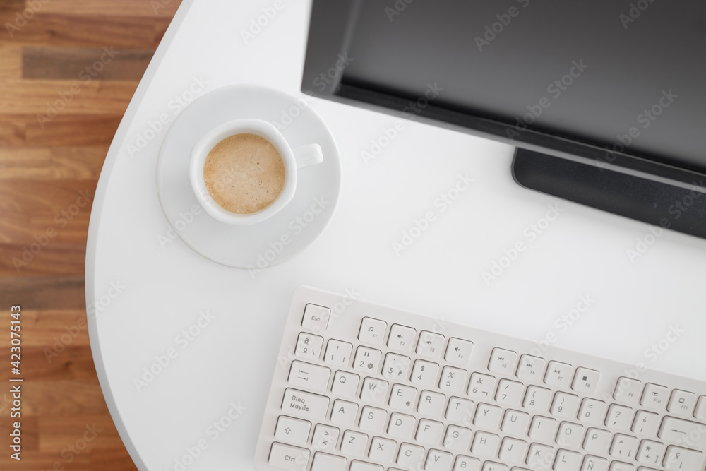 From above modern computer with black monitor and white keyboard placed on desk with coffee mug in office From above modern computer with black monitor and white keyboard placed on desk with coffee mug in office
