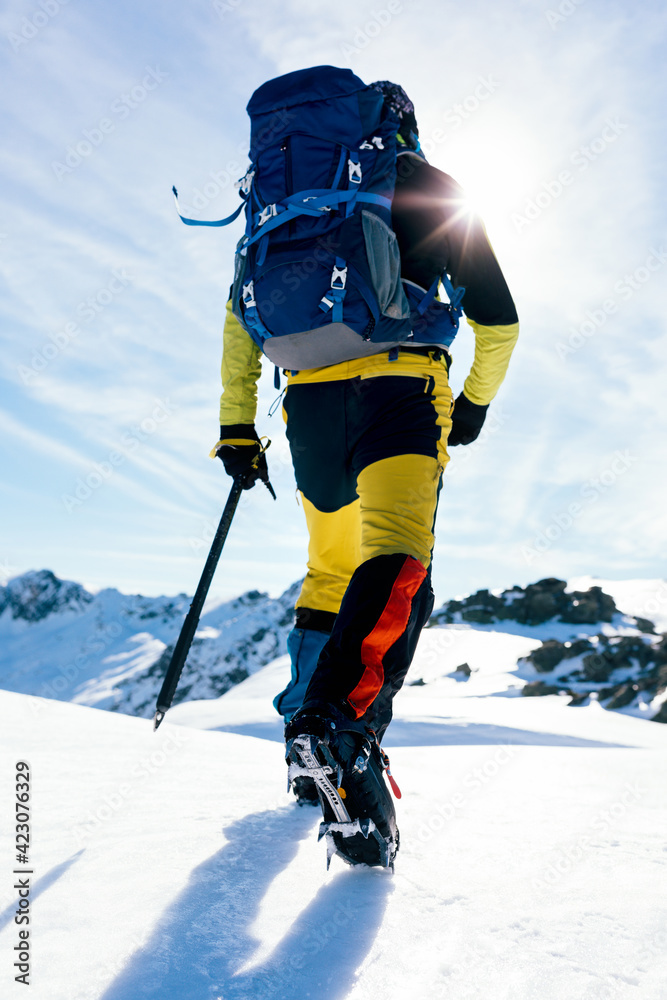 Back view of crop anonymous mountaineer in boots with crampons climbing  snowy mountain slope in sunny day in highlands Stock Photo | Adobe Stock