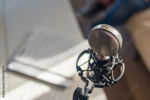 From above of metal vintage mic placed on music notes during rehearsal in daylight