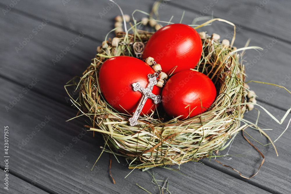 colored deep red Easter eggs in nest with cross rosary  top view background, selective focus image. Happy Easter card	
