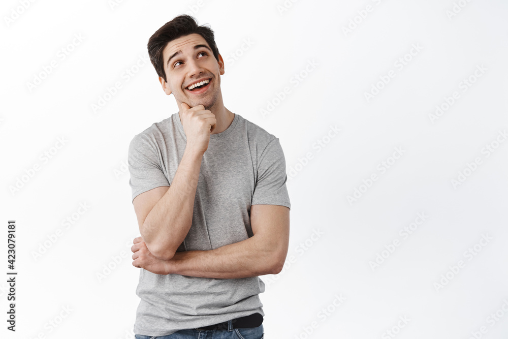 Happy smiling man thinking, imaging something with pleased dreamy face, have interesting idea, looking at upper right corner promo banner, white background Happy smiling man thinking, imaging something with pleased dreamy face, have interesting idea, looking at upper right corner promo banner, white background
