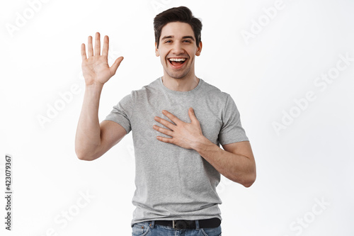 Obraz na płótnie Happy smiling adult man introduce himself, raising hand and hold palm on chest,