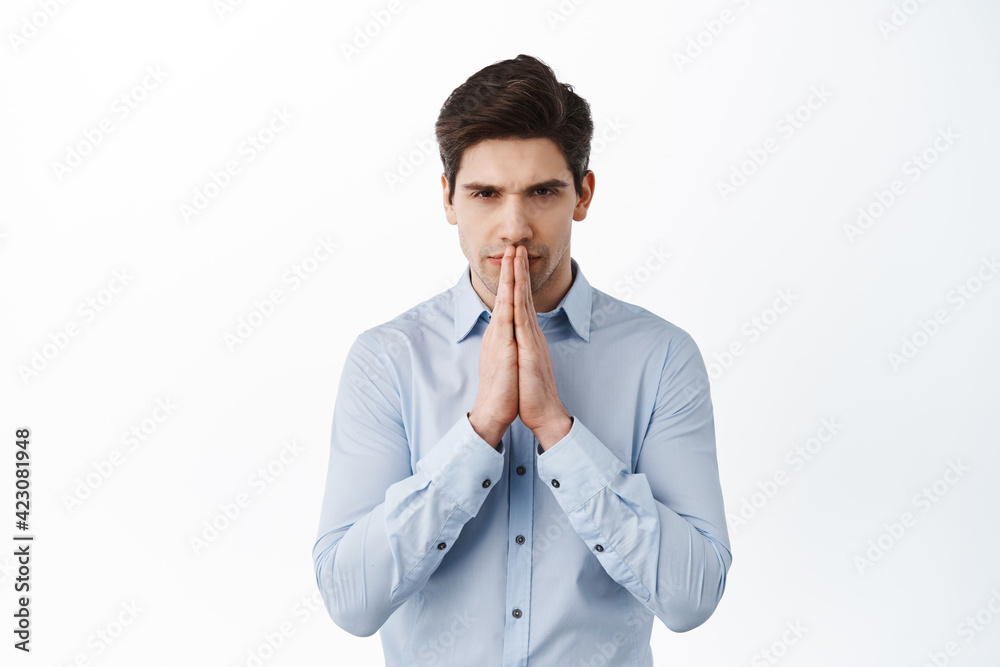 Serious businessman praying, waiting for news with begging gesture, expect or anticipate something, standing over white background Serious businessman praying, waiting for news with begging gesture, expect or anticipate something, standing over white background