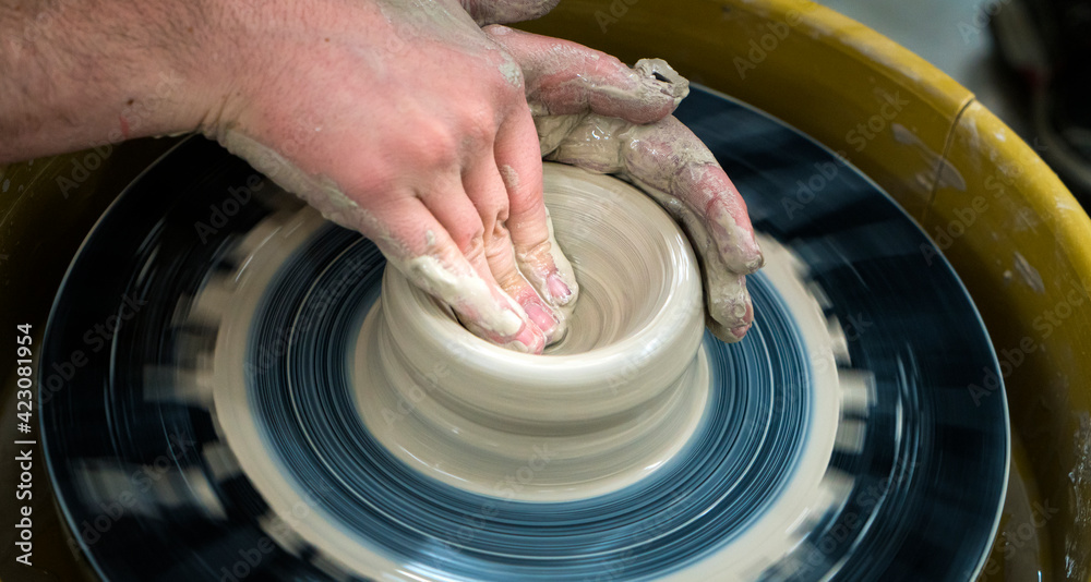 close up of hands of a potter at his potter's wheel
