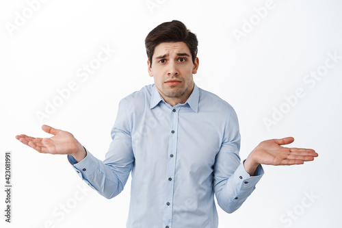 I dont know. Clueless corporate guy, office worker shrugging shoulders and look confused, standing puzzled against white background photo
