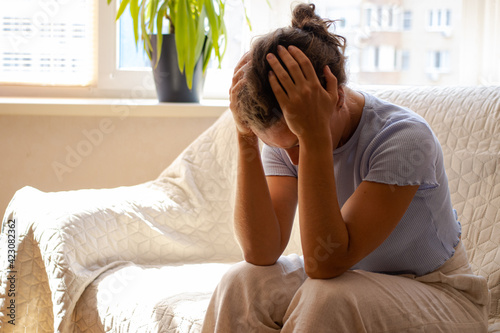 Εκτύπωση καμβά Frustrated depressed young woman hide face in hands, crying, sitting on sofa at home