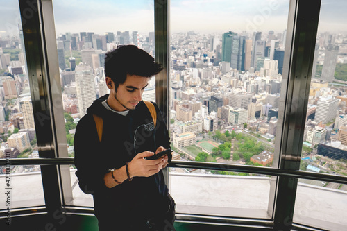 Photography Young tourist guy in his phone with the panoramic view of Tokyo skyline, Japan