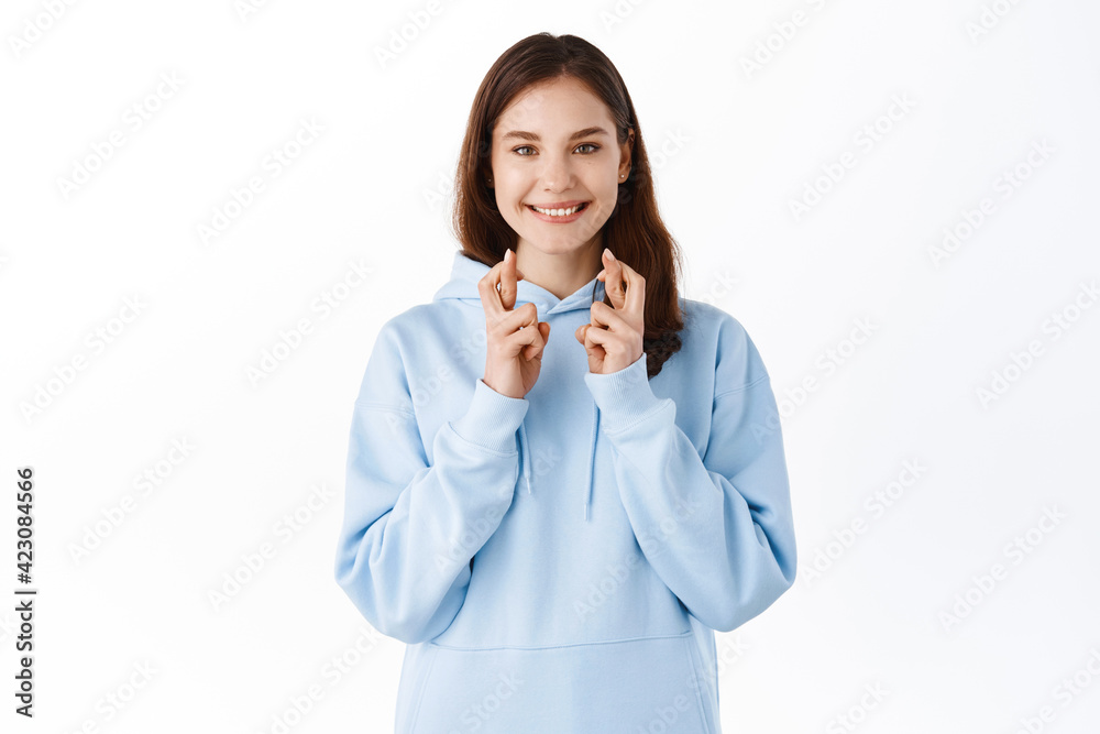 Having high hopes. Smiling positive girl student making wish, anticipating good news, looks hopeful and cross fingers for good luck, praying for dream come true, white background Having high hopes. Smiling positive girl student making wish, anticipating good news, looks hopeful and cross fingers for good luck, praying for dream come true, white background