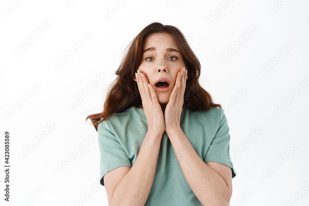 Portrait of shocked worried woman holding hands on face, looking concerned and nervous, pity for someone in bad situation, standing troubled against white background Portrait of shocked worried woman holding hands on face, looking concerned and nervous, pity for someone in bad situation, standing troubled against white background