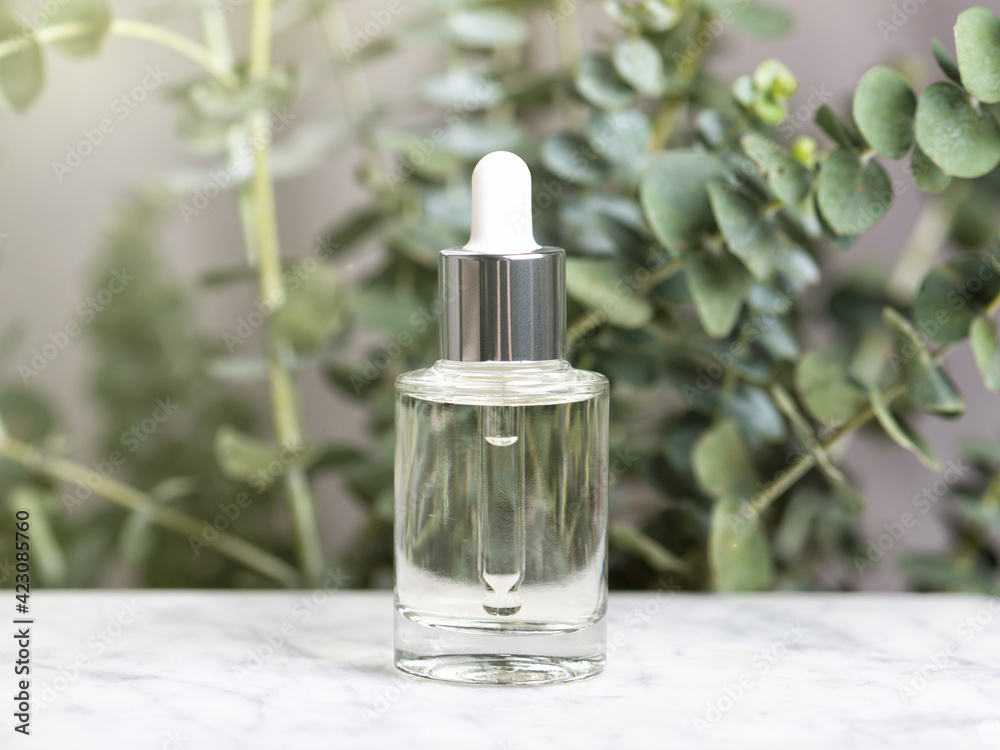 Glass bottle of essence or serum with natural eucalyptus leaves