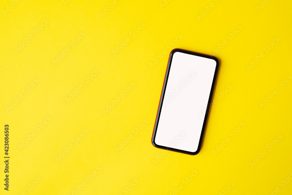 Phone with empty screen on yellow background, top view Phone with empty screen on yellow background, top view