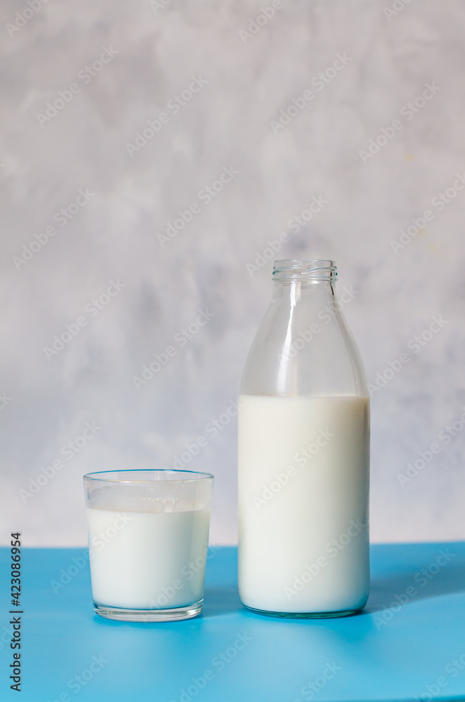 A bottle of milk or kefir and a glass nearby on a gray background. A healthy, nutritious, tasty product. Close-up copy space A bottle of milk or kefir and a glass nearby on a gray background. A healthy, nutritious, tasty product. Close-up copy space