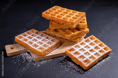 Fotografie Sweet waffles sprinkled with powdered sugar prepared for serving