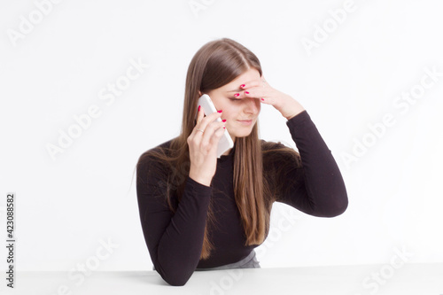 young brunette in a black jumper, sitting on a white isolated background