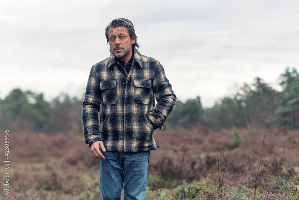 Man with stubble beard in a checkered coat in a rainy heathland. Man with stubble beard in a checkered coat in a rainy heathland.