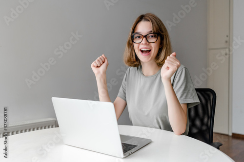 young happy woman smiling sitting with laptop in the apartment won the prize