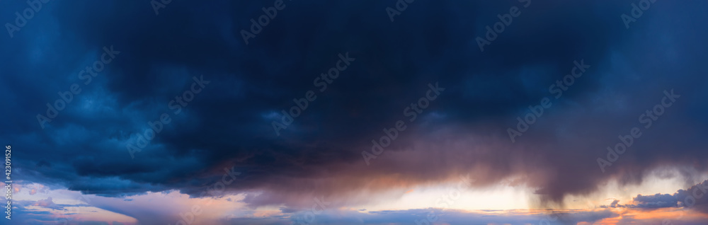 Dramatic sky with dark rainy clouds at sunset.