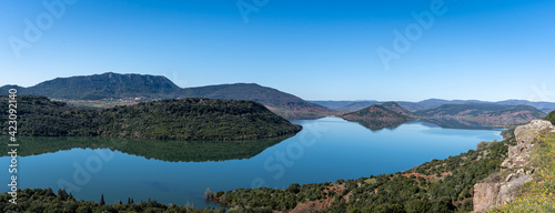 Vue panoramique sur un lac calme et bleu , bordé de montagnes vertes arborées