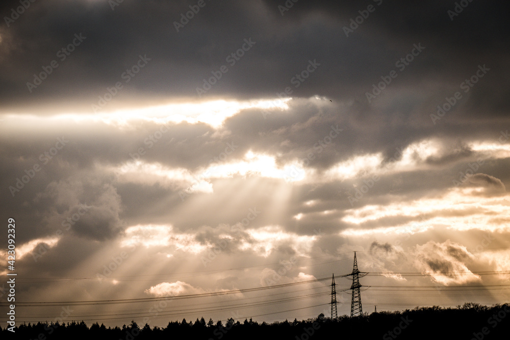 Fototapeta premium Lichtstrahlen über Hochspannungsmasten einer Überlandleitung