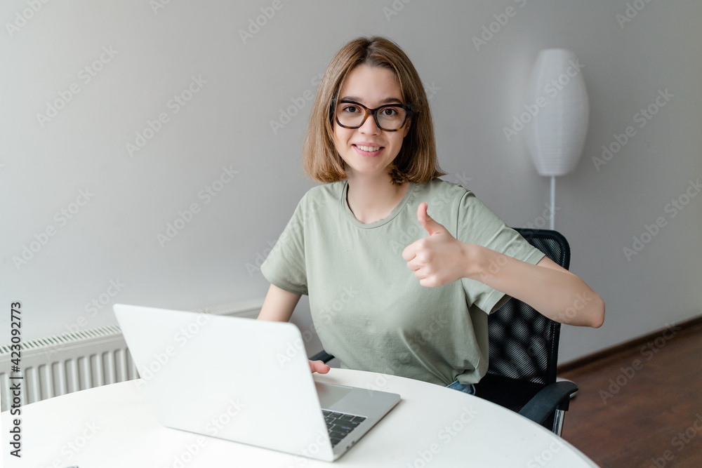 Happy Smiling Girl Working Online Or Studying And Learning While Using Notebook showing thumb up. Freelance Work Concept Happy Smiling Girl Working Online Or Studying And Learning While Using Notebook showing thumb up. Freelance Work Concept