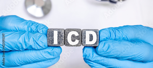 ICD Implantable cardioverter defibrillator - word from stone blocks with letters holding by a doctor's hands in medical protective gloves