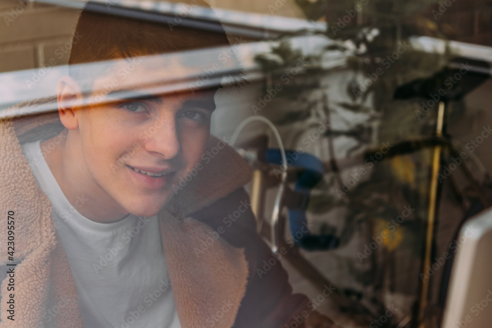 portrait of male teenager behind window pane portrait of male teenager behind window pane