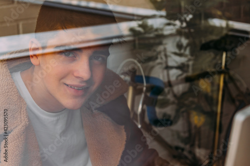 portrait of male teenager behind window pane