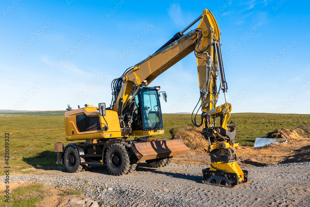 Wheeled excavator in a road contruction site in the countryside of Iceland at sunset in summer