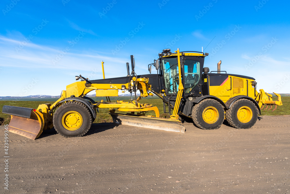 Motor grader in a road construction site in the countryside under blue sky Motor grader in a road construction site in the countryside under blue sky