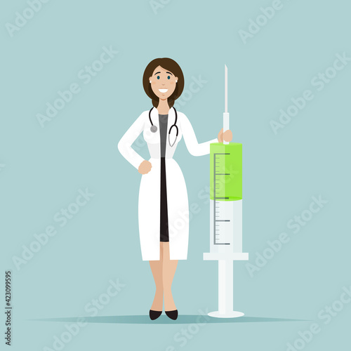 The female doctor smiles and stands next to a large syringe. A syringe with a vaccine.