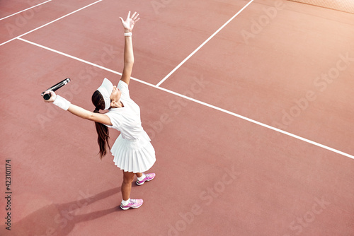 Pretty girl plays tennis on the court outdoors. She prepares to beat on a ball. Woman wears a light blue sportswear with white sneakers © Friends Stock
