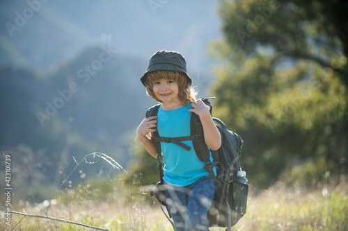 little boy with backpack hiking in scenic mountains. Boy local tourist goes on a local hike