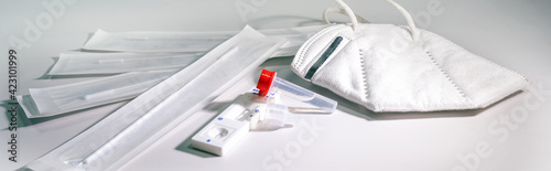 Covid-19 rapid antigen self test for diagnostic at home and a ffp-2 mask on a light gray background, panoramic format, copy space, selected focus, narrow depth of field photo