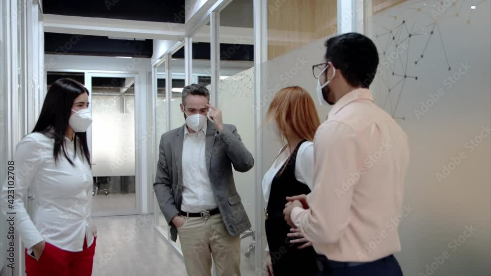 Grupo de gente trabajando en pasillo de oficina con mascarillas en distanciamiento social Grupo de gente trabajando en pasillo de oficina con mascarillas en distanciamiento social