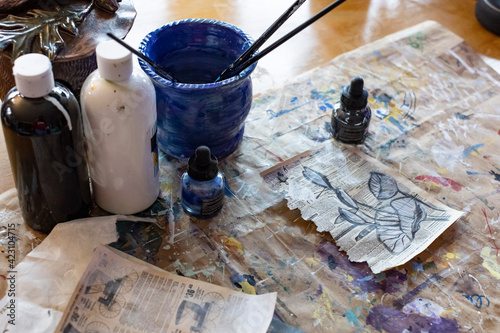 Slika na platnu Art supplies on a desk with a drawing of flower buds in natural light
