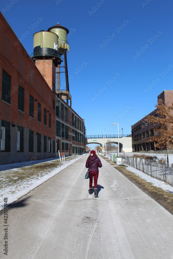 Woman walking on the Dequindre Cut Greenway in Detroit in winter with vintage water towers