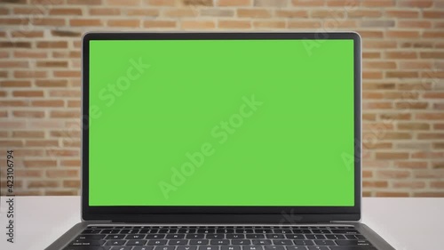 Close up display computer desktop with mock-up green screen on white table, Slow motion laptop green screen on desk and brown brick wall background, Blank of mockup notebook PC, Chroma key monitor.