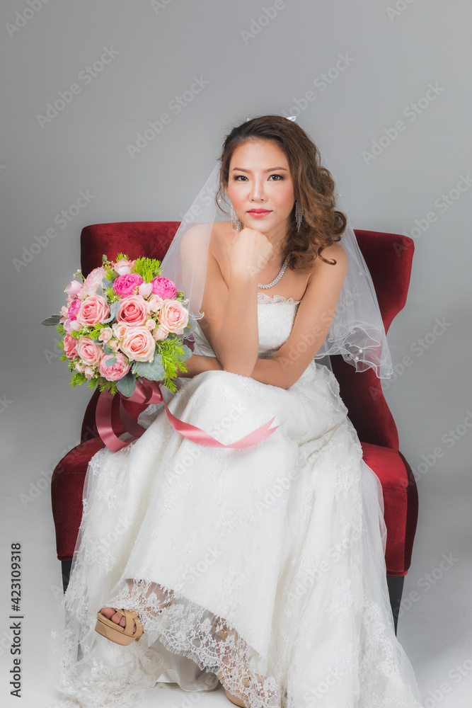 Asian bride sitting and holding a bouquet..