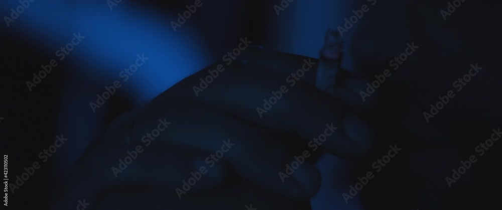 Close up of a man smoking a cigarette outside at night, dealing with anxiety and post trauma Close up of a man smoking a cigarette outside at night, dealing with anxiety and post trauma