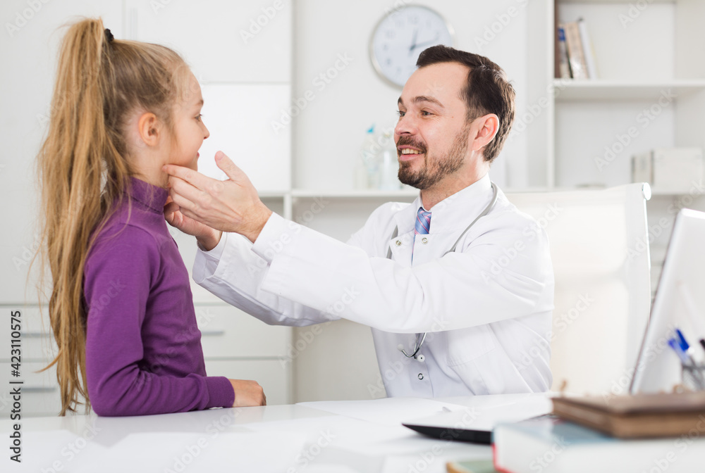 Obraz premium Little smiling girl visiting consultation with man doctor in hospital