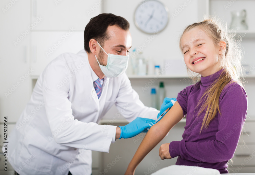 Obraz premium Young male doctor ready to make injection to teenage female visitor in hospital